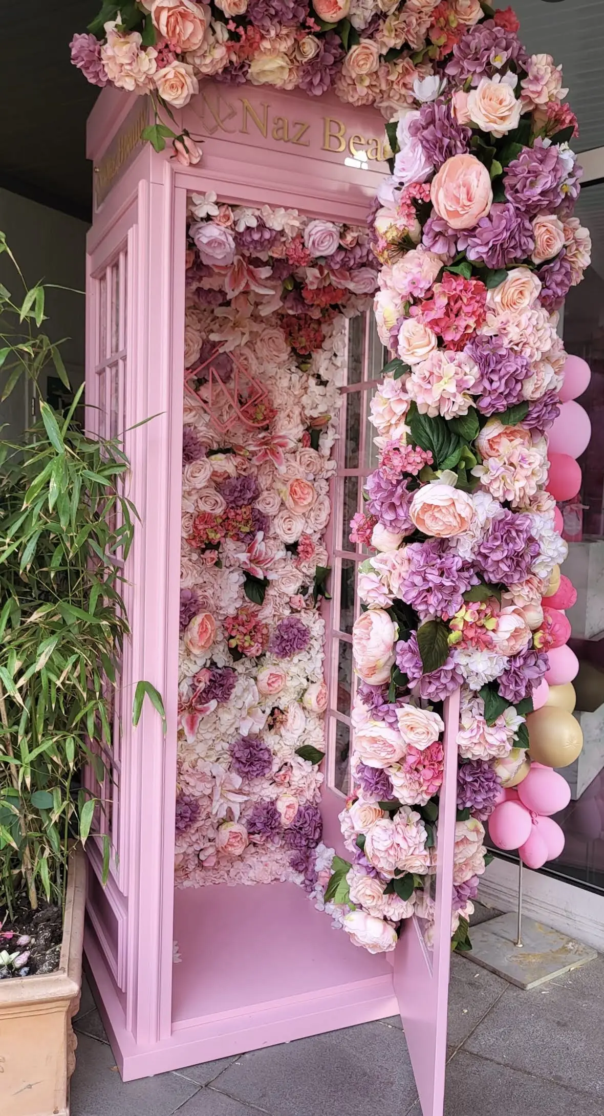 Innenraum der rosa Telefonzelle: eine Wand aus Rosen, Hortensien und Pfingstrosen in Rosa, Apricot und Flieder